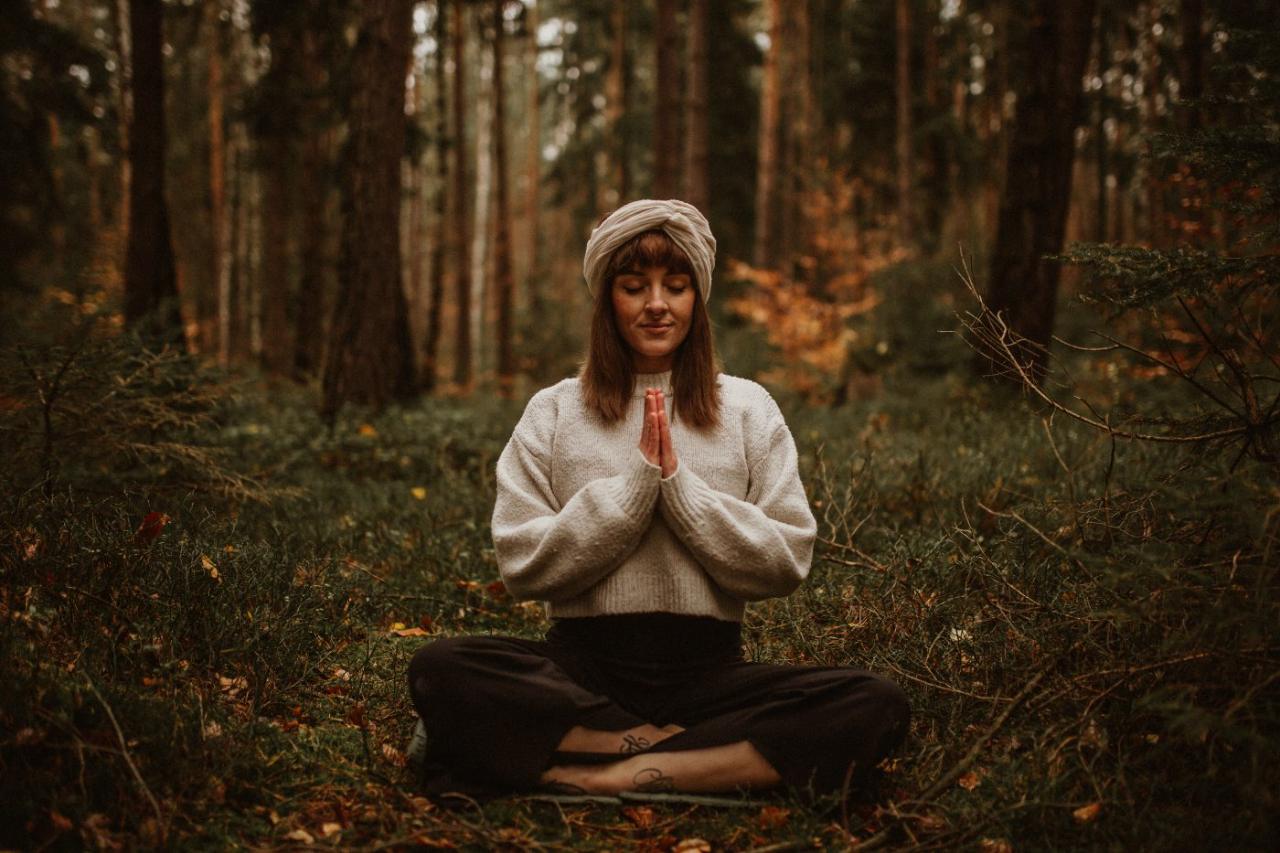 Anna in Andacht, Hände am Herzen im Wald