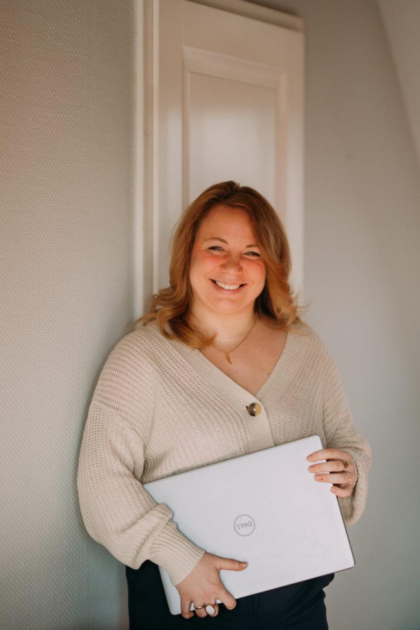 Janine lachend mit Laptop im Arm