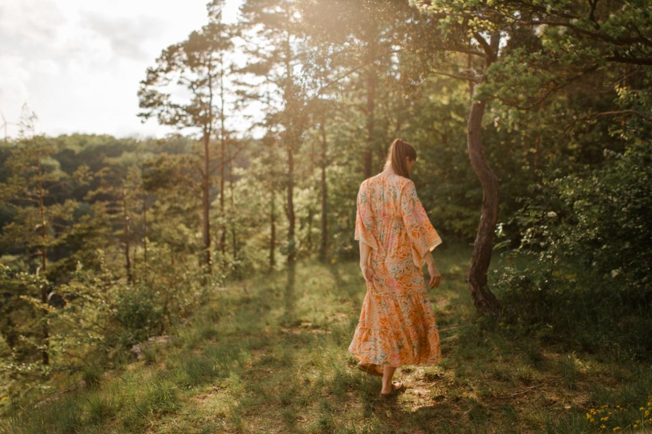Maria im orangefarbenen Kleid im sommerlichen Wald