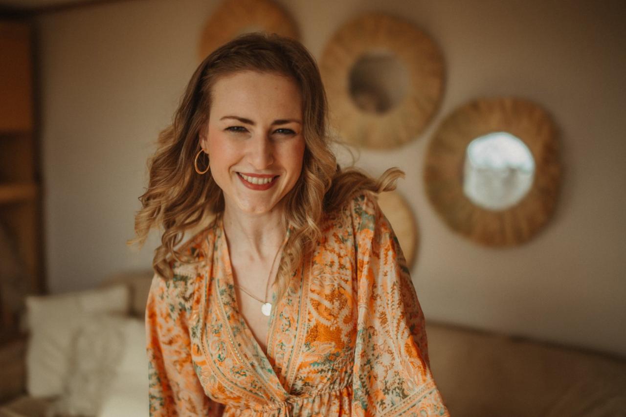 Sarah lachend vor der Wand aus Sonnenspiegeln