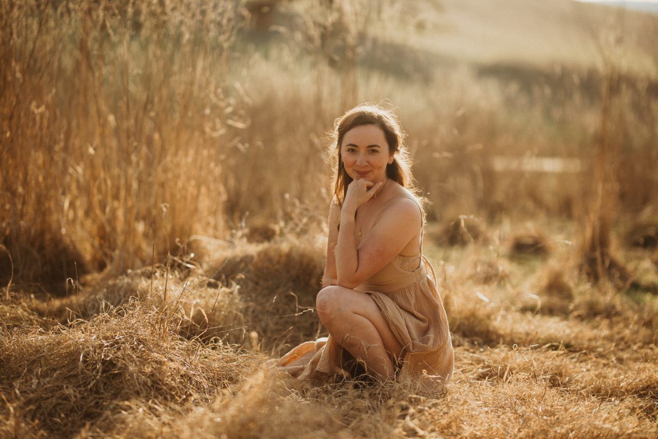 Vanessa sitzend im goldenen Feld im Abendlicht