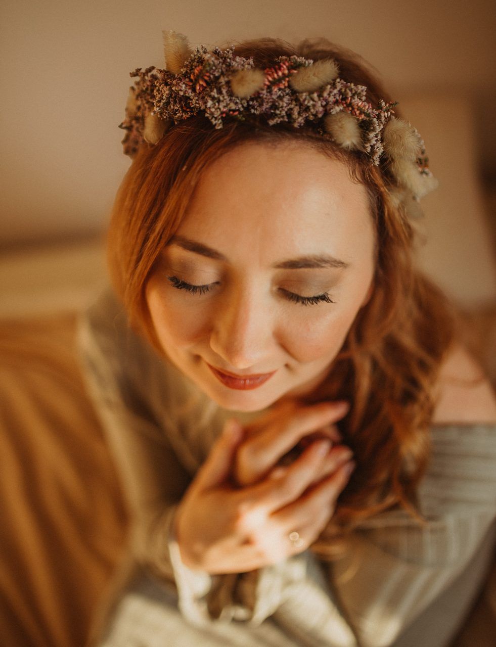 Vanessa mit Blumenkranz, Hände am Bauch im warmen Licht — wild.woman.fotografie